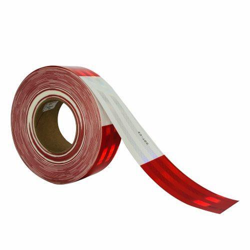 Un rollo de cinta reflectante roja con un poco de cinta desenrollada, que muestra una superficie brillante y texturizada. la cinta está enrollada y la parte desenrollada se extiende hacia la derecha, colocada sobre un fondo blanco liso.