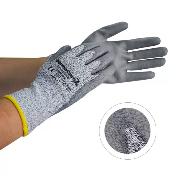 Un primer plano de una mano que lleva un guante de seguridad con textura gris y una pulsera amarilla. El recuadro muestra una vista detallada de la textura de la tela del guante. nombre de la marca "safety grip" visible.