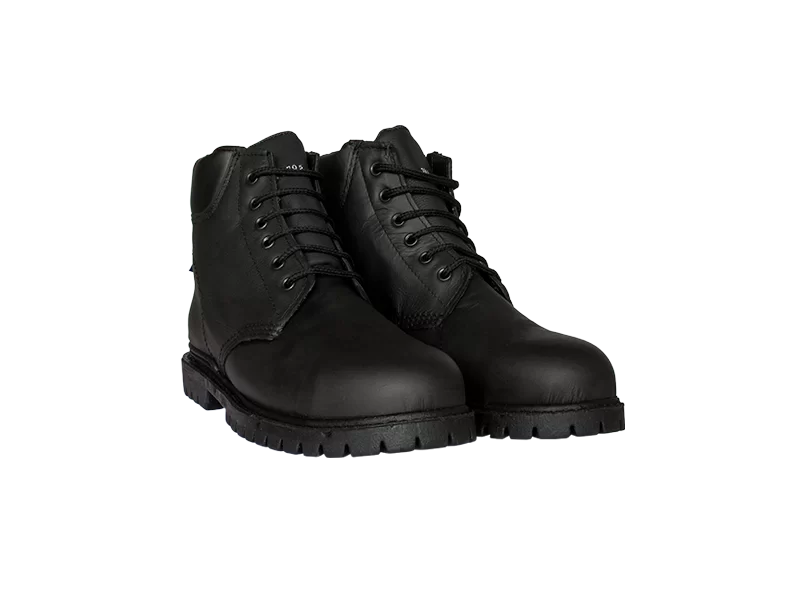 Un par de botas con cordones de cuero negro y suela gruesa sobre un fondo verde liso. Las botas parecen resistentes y están diseñadas para durar, con costuras reforzadas y puntera redonda.