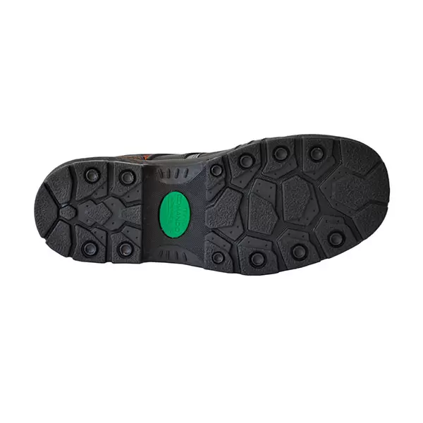 Un primer plano de la suela de un zapato que muestra un patrón complejo con formas hexagonales e irregulares. la suela es predominantemente negra con un toque naranja y un parche circular verde en la zona del mediopié.