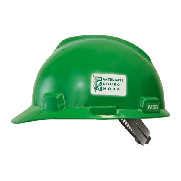 Un casco de seguridad de color verde brillante con una pegatina blanca que dice "manténgase seguro ahora" y el logo de msa en el frente. el casco tiene un ligero brillo y un trinquete ajustable visible en la parte posterior.