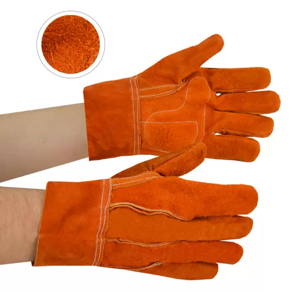 Un par de guantes de soldadura de gamuza naranja en manos humanas, que muestran la vista frontal. un círculo insertado muestra un primer plano del material texturizado del guante. Los guantes cuentan con costuras visibles y refuerzos cosidos en las palmas y los dedos.